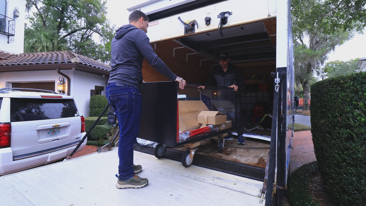 Installers unloading a new glass aquarium and equipment at a Central Florida home